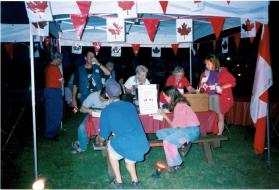 People at Coronation park during the Oakville Waterfront Festival filling out Speak Out!... Canada... Pensons-y! Ballot entries at night time