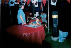 People at Coronation park during the Oakville Waterfront Festival filling out Speak Out!... Canada... Pensons-y! Ballot entries at night time